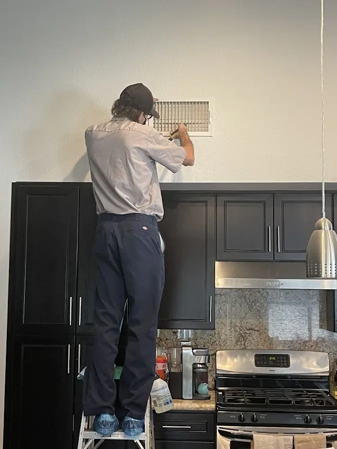 Technician inspecting an air vent during HVAC service in Centerville